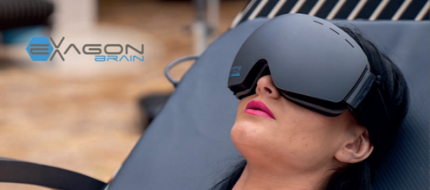 A woman reclining while wearing the Exagon Brain brainwave entrainment goggles