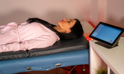 A person asleep on the PEMF mat with the tablet control unit beside the bed
