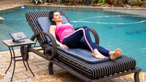 A woman relaxing on a lounger beside a pool